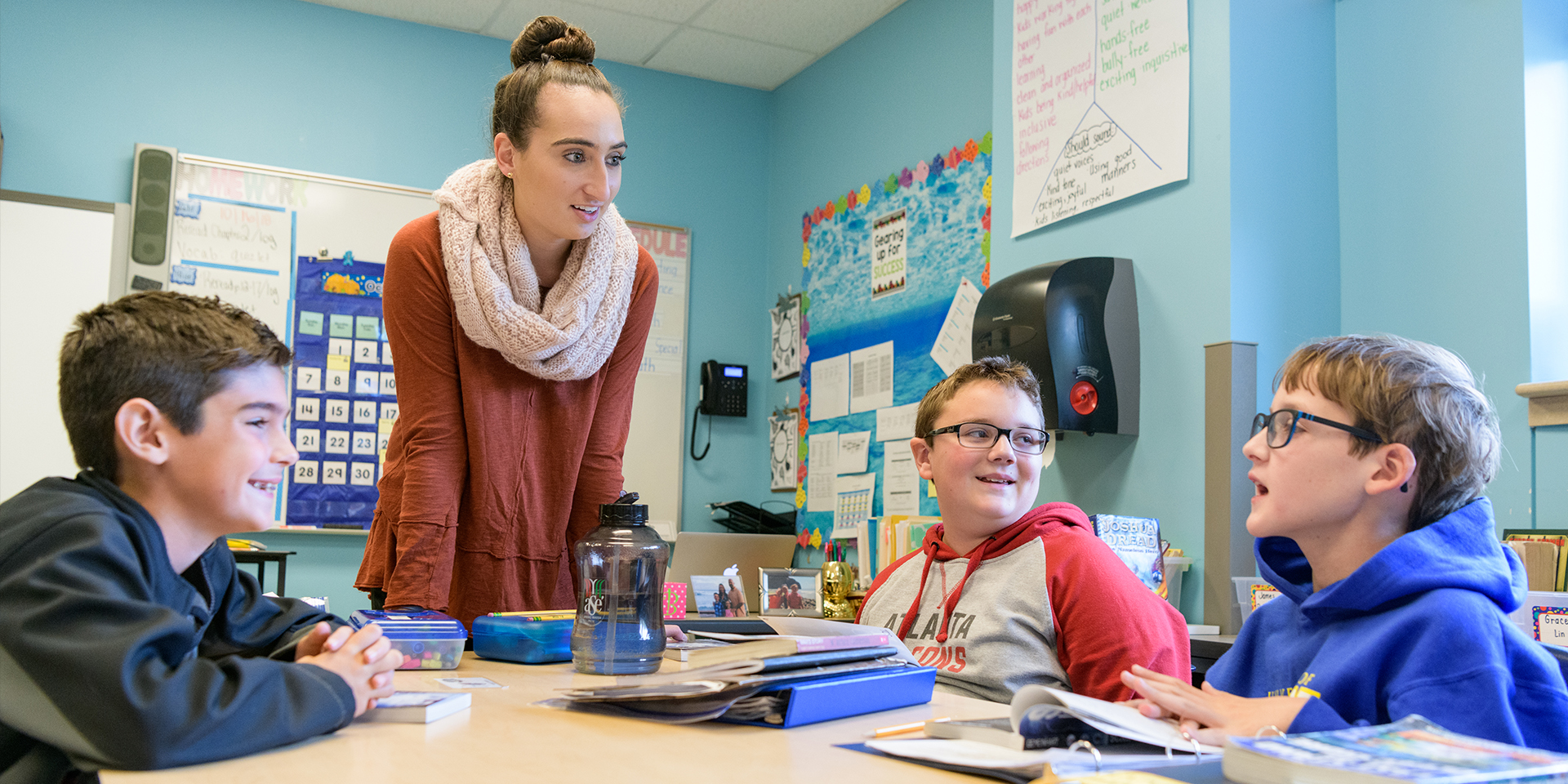 Student teacher talks to three elementary school students