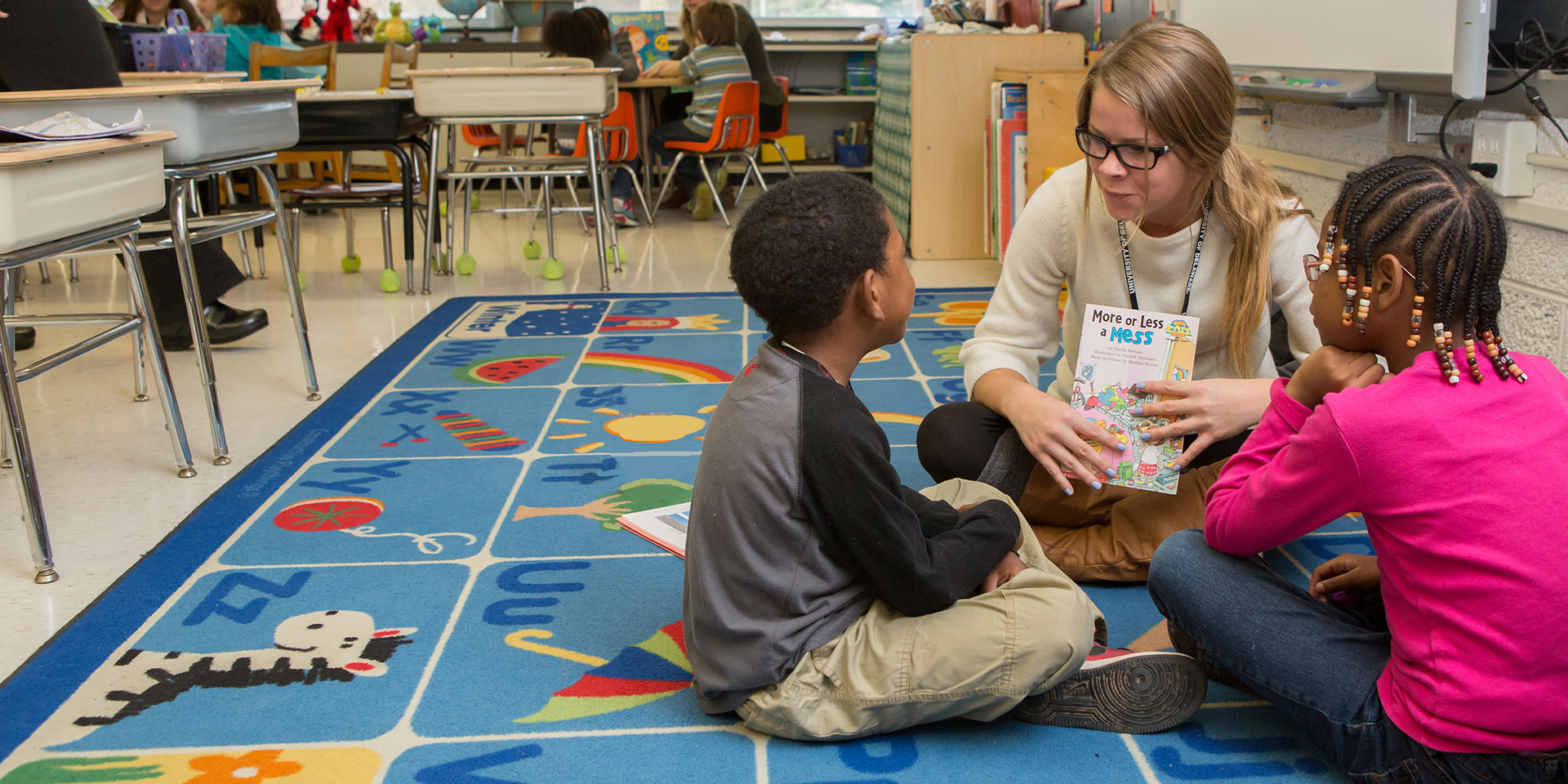 UD student mentoring students on carpet