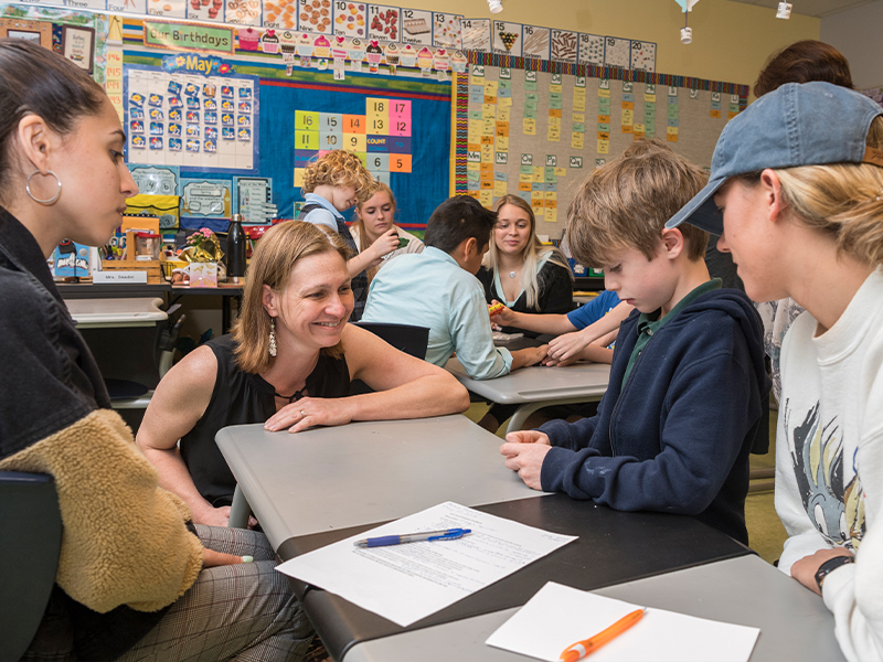 Dr. Jennifer Galllo Fox talks to a child and two UD students at The College School