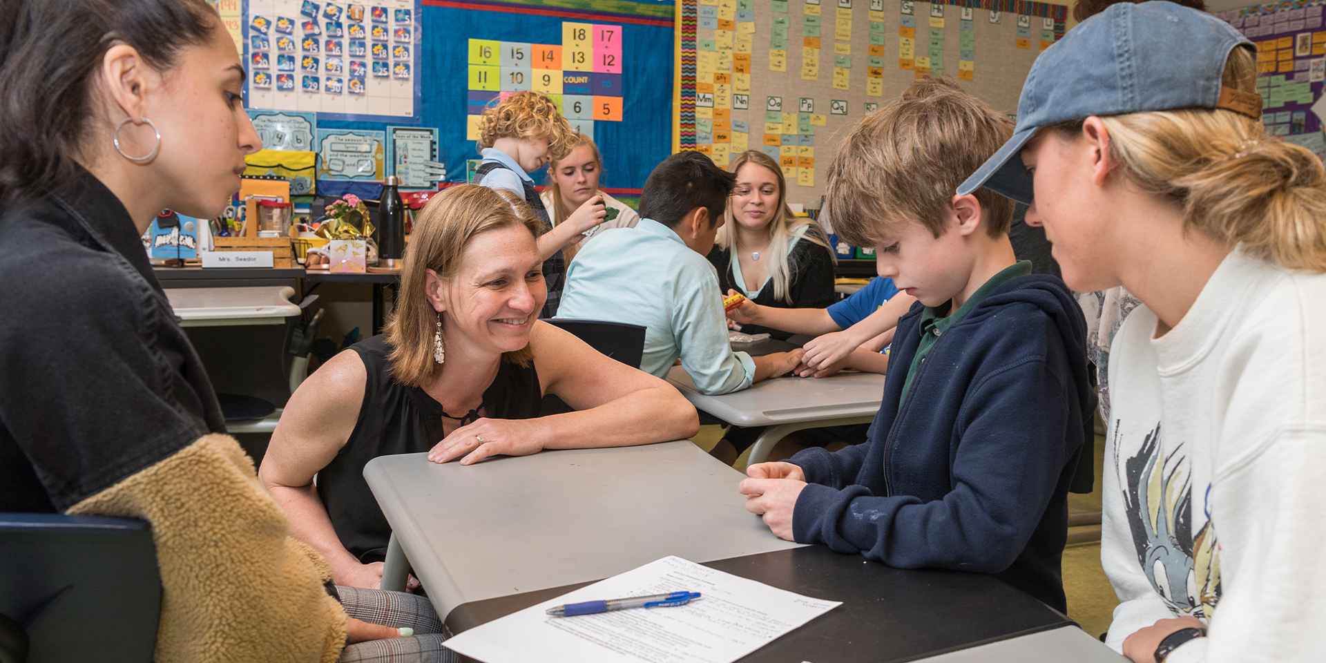 Dr. Jennifer Galllo Fox talks to a child and two UD students at The College School