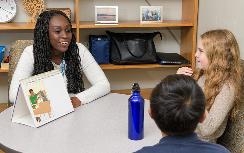 Graduate student speaks with two students at The College School