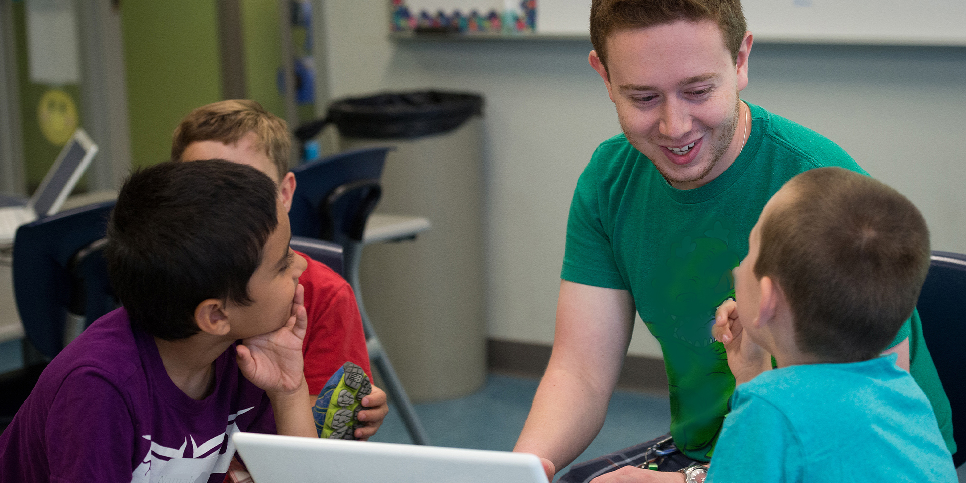 Student teacher with three children doing assignment on a laptop